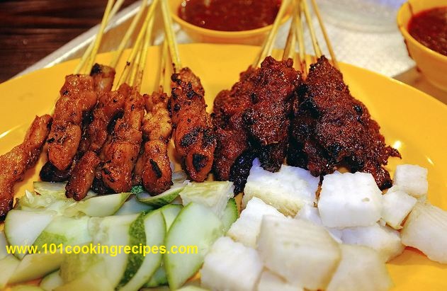 Malaysia Satay with Satay Peanut Sauce, Cucumber, Ketupat Nasi (compressed rice cakes) on the right.